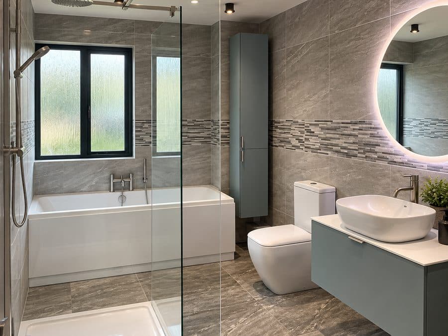 Luke Smith’s grey stone-effect bathroom with a glass shower screen, bath and wall-hung vanity