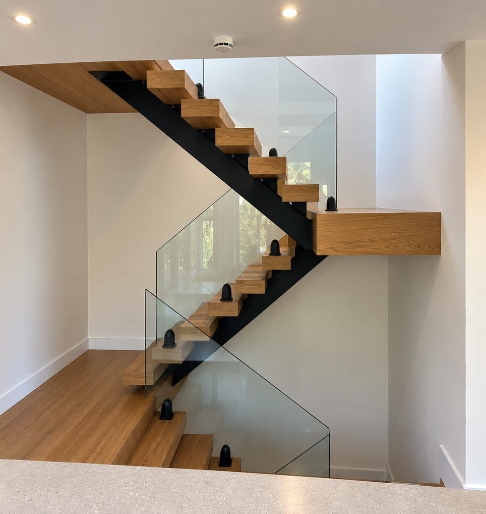 Luke Smith’s oak staircase with open treads, a black steel spine and frameless glass balustrade
